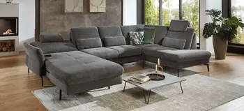 Großzügige graue Wohnlandschaft mit verstellbaren Kopfstützen, Cordbezug und Deko Kissen in modernem Wohnzimmer mit Kamin und großen Fenstern.